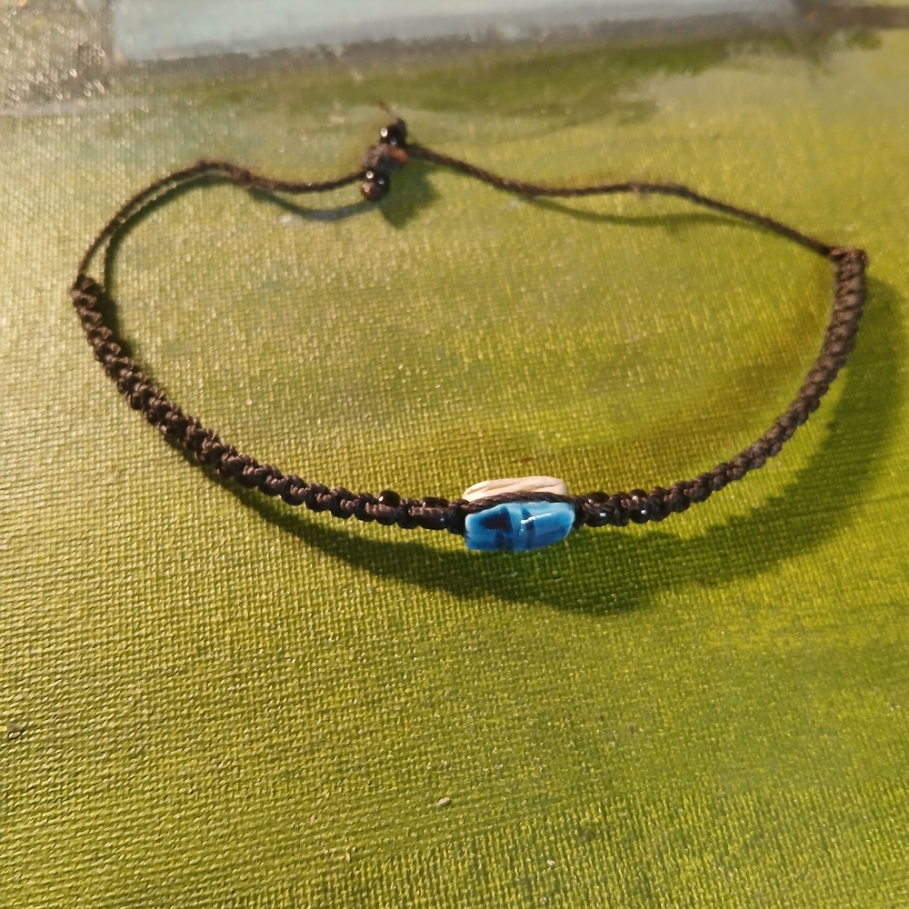 This is a black macrame square knot bracelet with central blue stone bead.